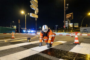 Une photo d'ouvriers entrain de poser de la signalisation horizontale, des bandes d'aides à l'orientation à Paris