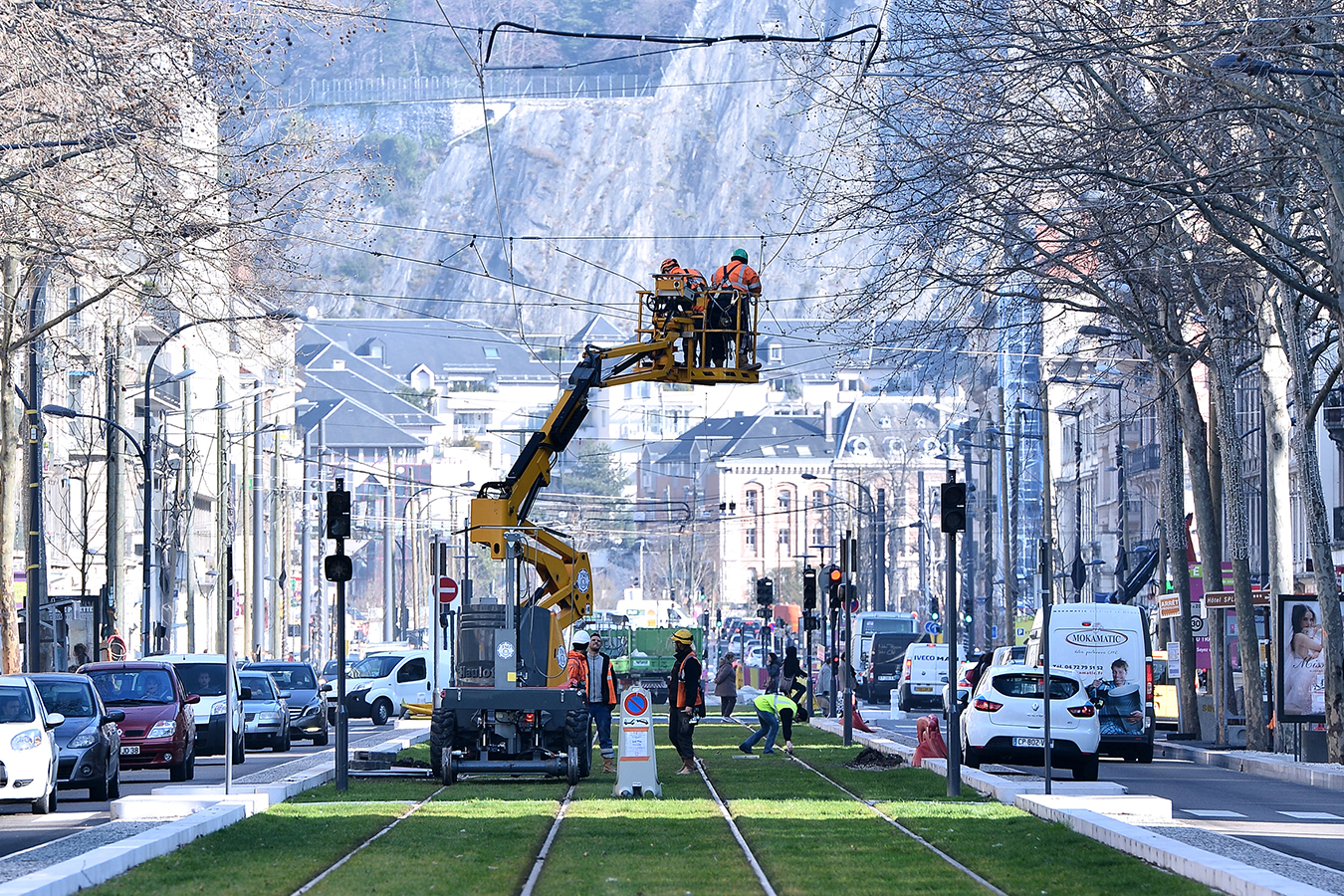 Deux ouvriers sur un engin réalise l'électrification d'une ligne de tramway.